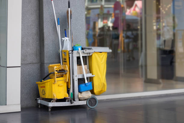 A yellow and green cleaning cart labeled "Shoddy Janitorial Cleaning" is parked outside a store entrance.
