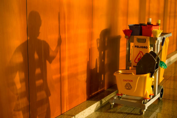 A yellow cleaning cart with a yellow bucket and a blue mop. The cart is parked outside a building