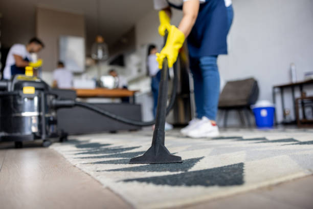 A man operates a vacuum to clean a glass door, showcasing professional commercial cleaning services.