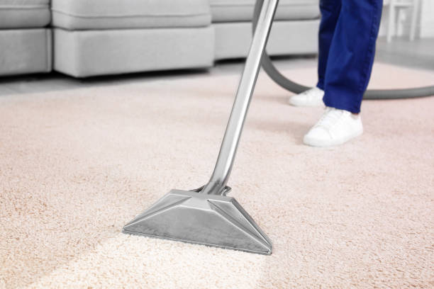 A man operates a vacuum to clean a carpet showcasing professional commercial cleaning services.