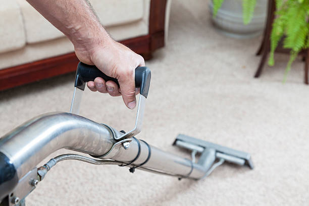 man cleans a carpet with a vacuum, showcasing commercial carpet cleaning services in action.