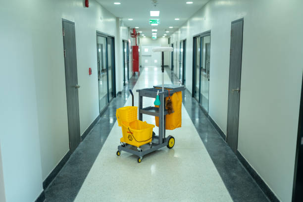 A commercial cleaning cart in yellow and black is located in the middle of a hallway, ready for cleaning tasks.