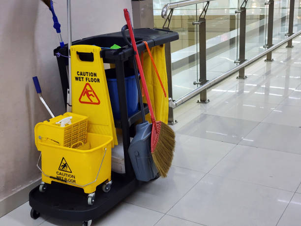  A yellow and black cleaning cart stands in the center of a hallway, representing a commercial cleaning service.