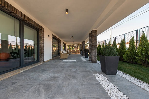 A walkway leading to a spacious patio, featuring a large planter filled with greenery.