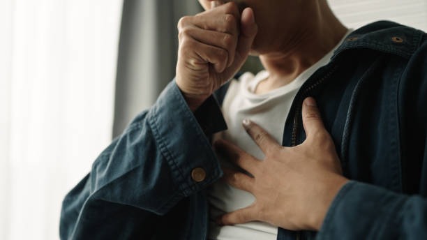A man clutches his chest while coughing, indicating discomfort, in a setting related to floor cleaning and maintenance.
