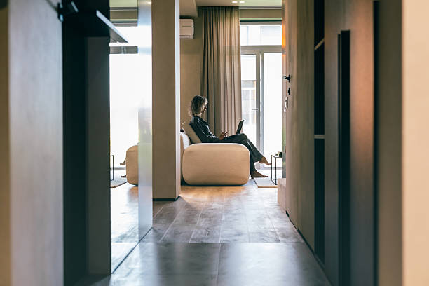 A person sitting in a chair in a hallway with a sign indicating floor cleaning in the background.